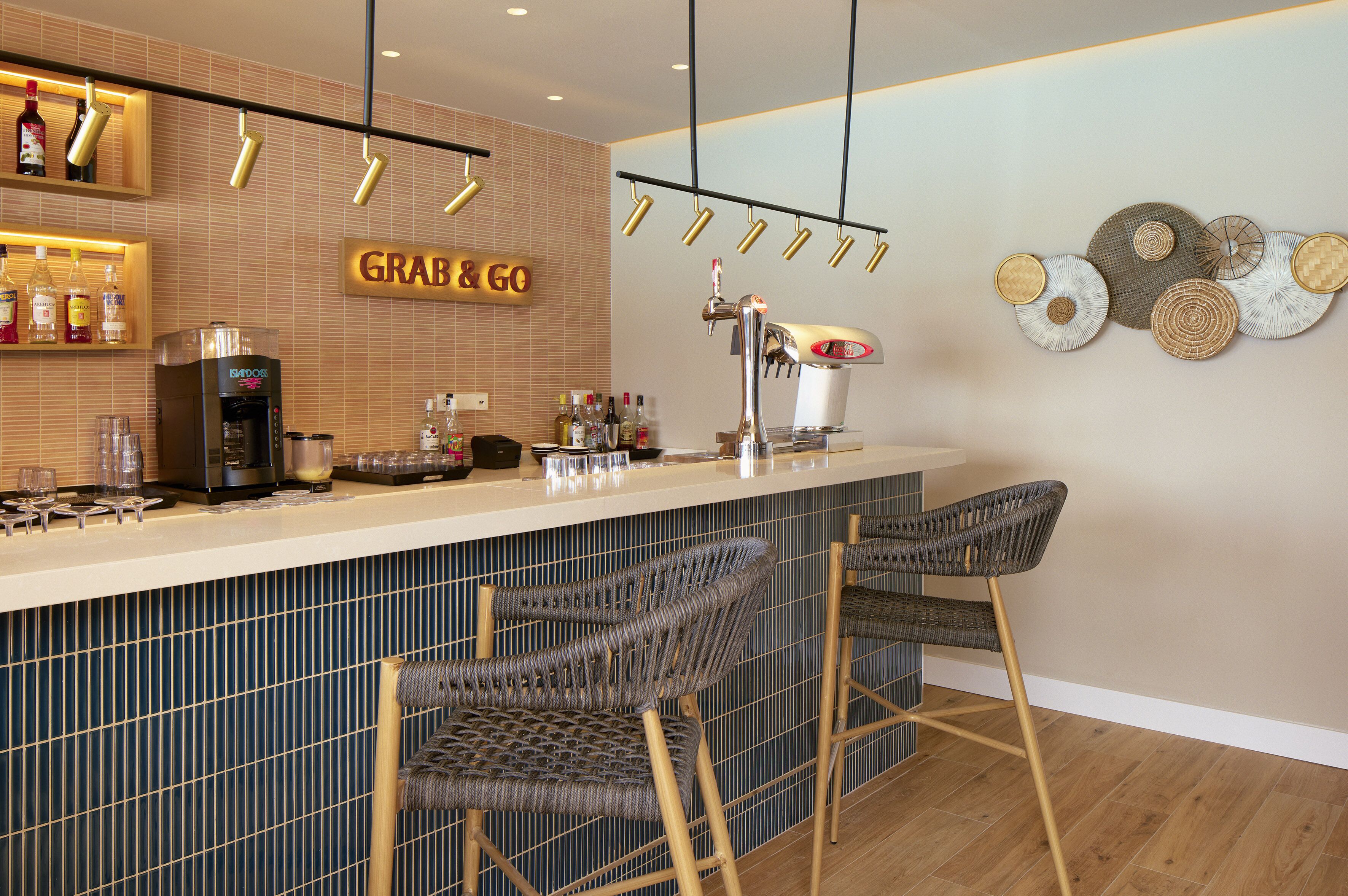 Zona de bar con un letrero 'Grab & Go', una máquina de café y taburetes.
