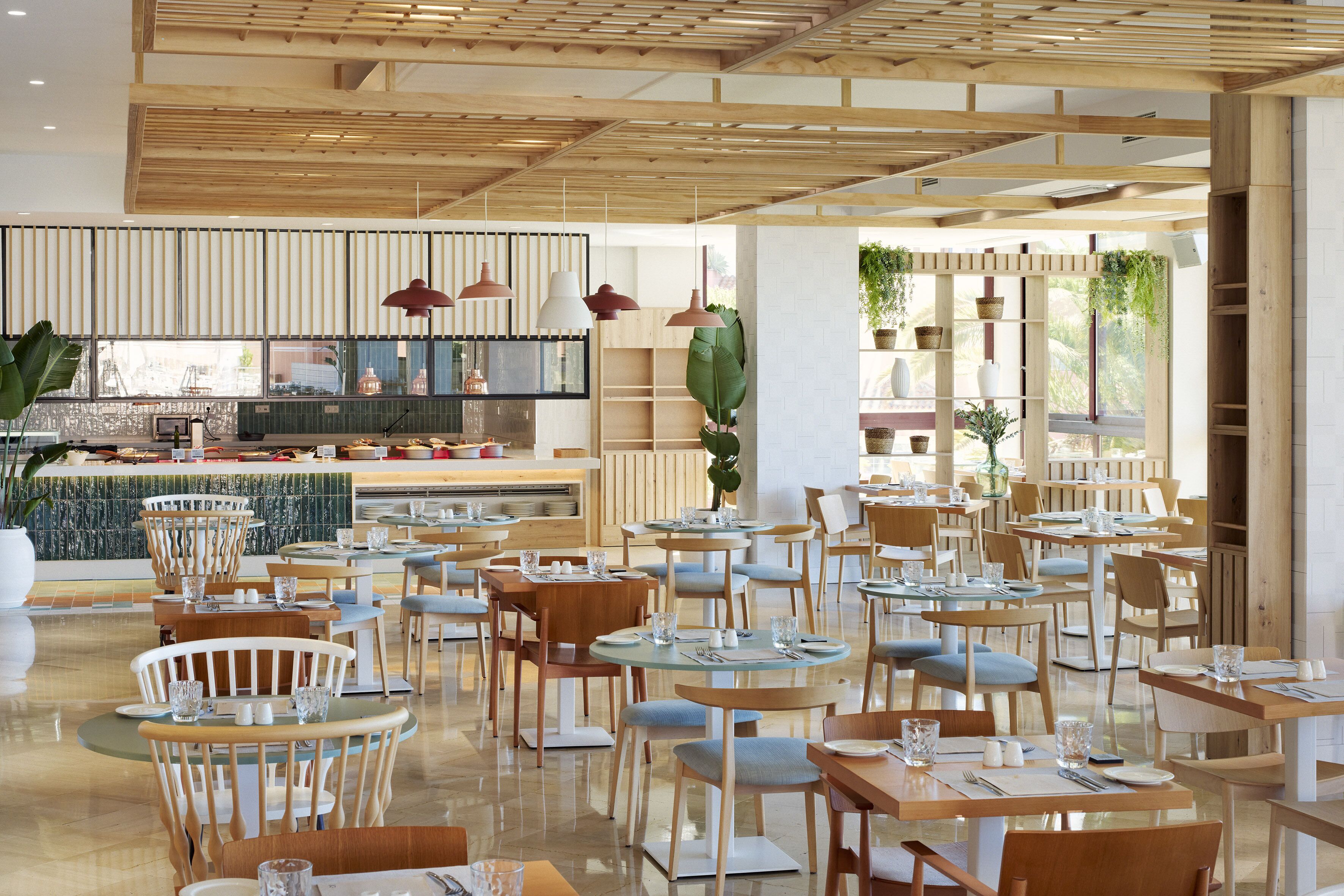 Un restaurant moderne avec des meubles en bois, des tables en verre et des luminaires suspendus.