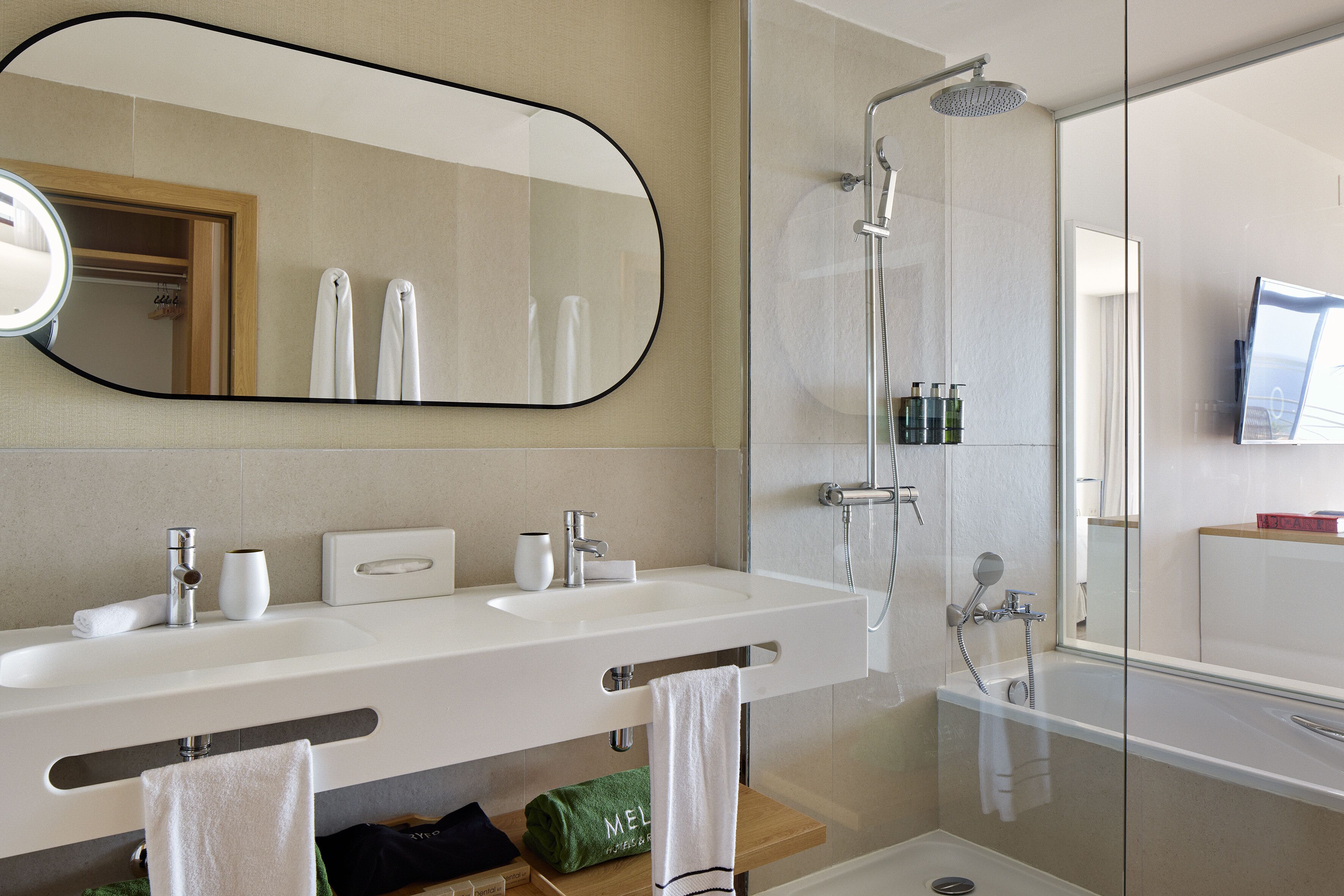 A modern bathroom with two sinks, a large mirror, a shower, and a bathtub.