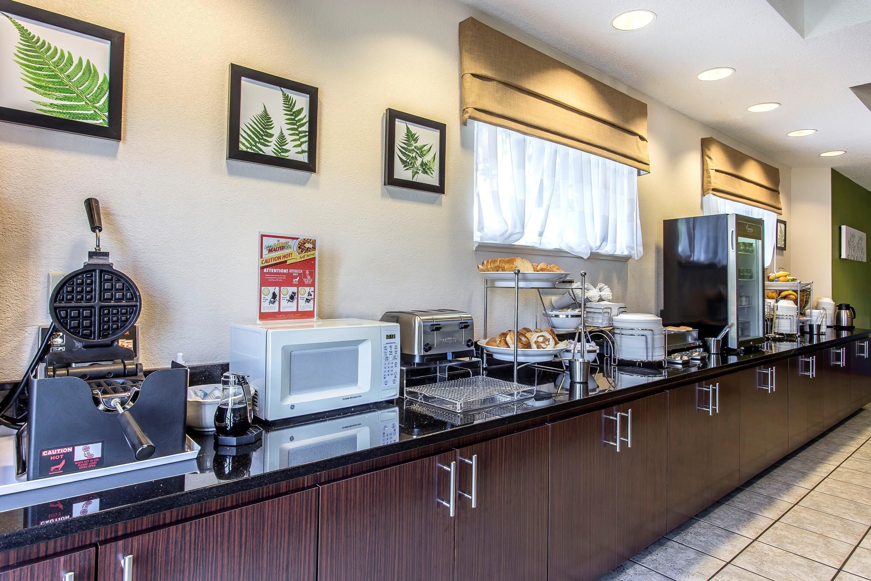 A kitchen with a waffle maker, microwave, toaster, and coffee maker.