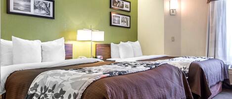 A hotel room with two beds, a nightstand, a lamp, and framed pictures on the wall.