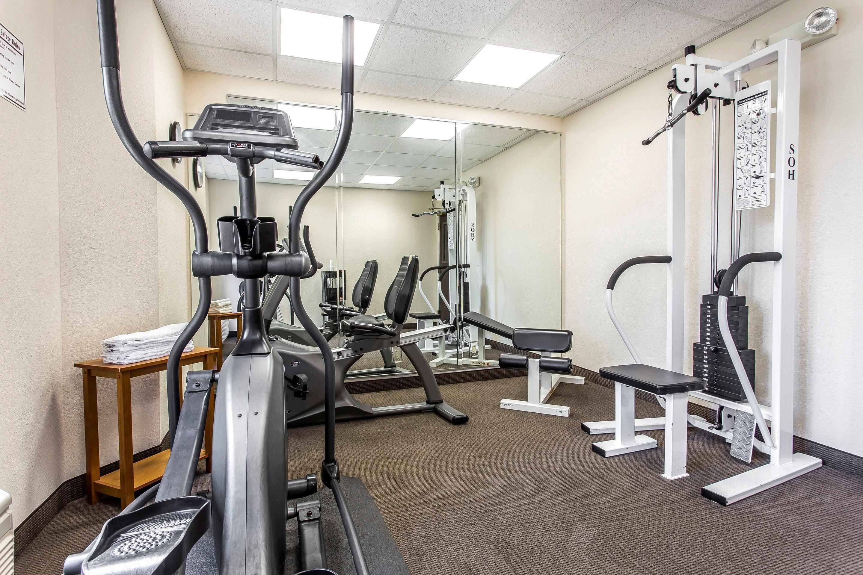 Et fitnesscenter med løbebånd, træningsudstyr og spejlvæg.