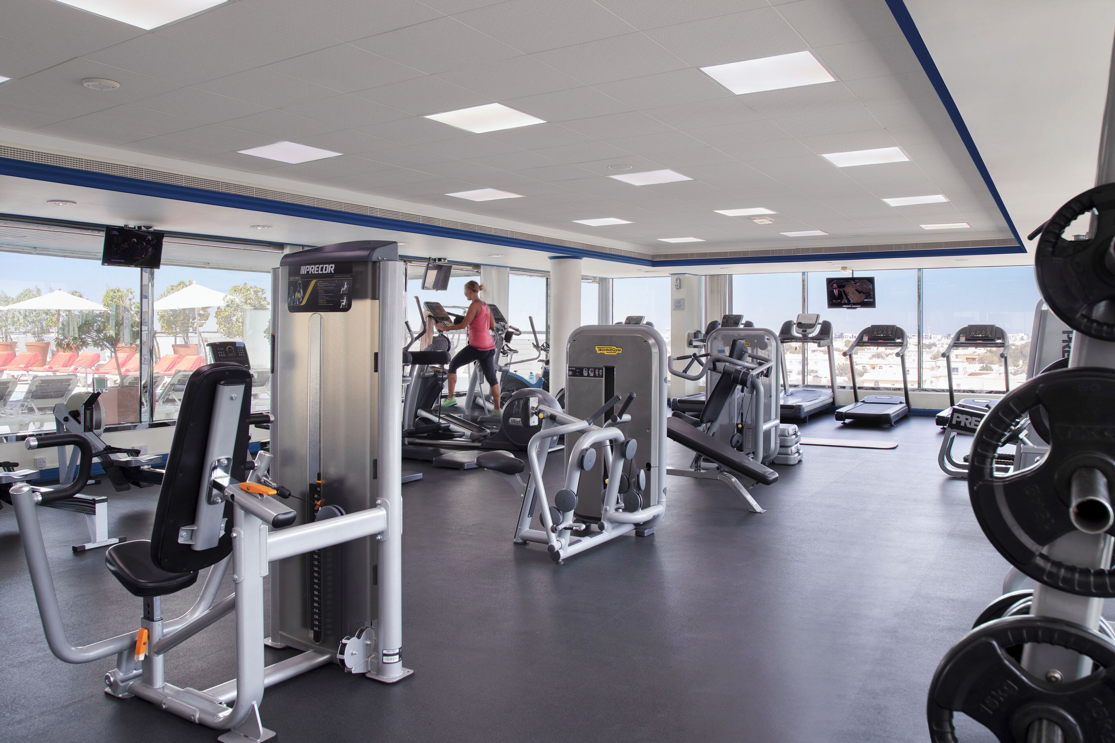 Ett gym med olika träningsmaskiner, ett löpband och utrustning för styrketräning.