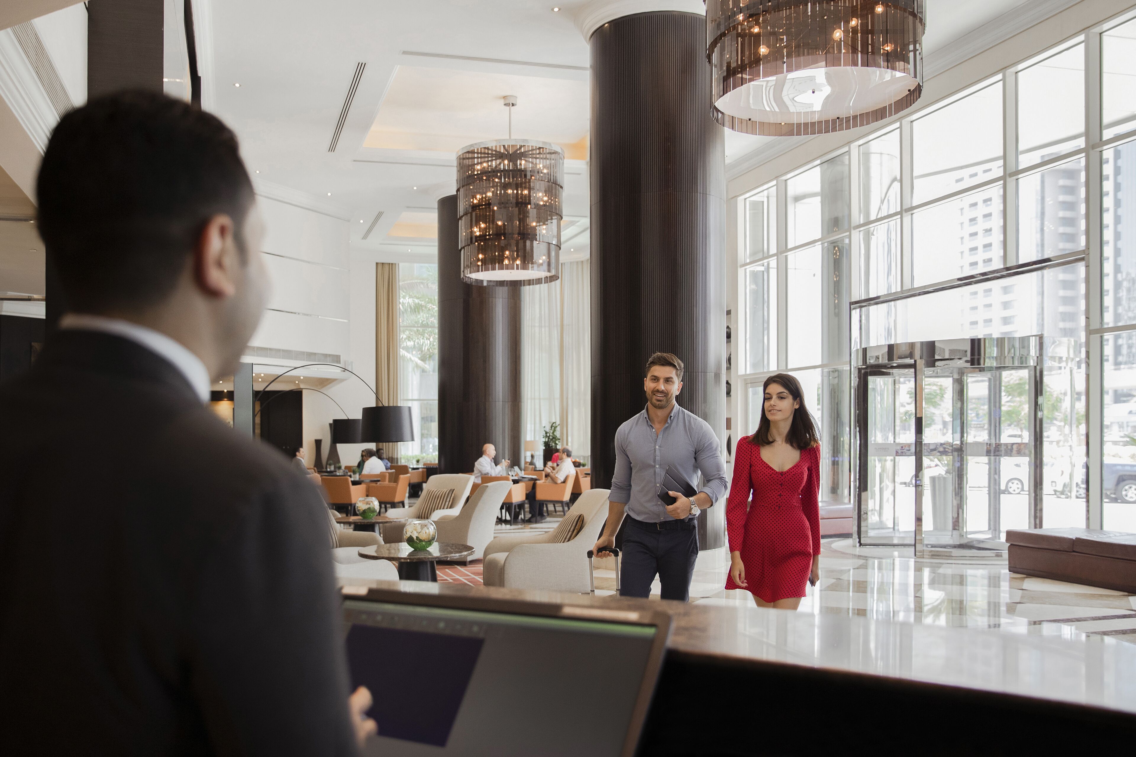 A spacious lobby with high ceilings, large windows, and modern chandeliers.