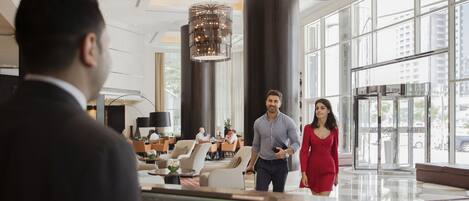 A spacious lobby with high ceilings, large windows, and modern chandeliers.