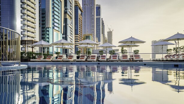 A modern hotel pool with sun loungers and umbrellas, surrounded by high-rise buildings. - Towers Rotana (Dubai)
