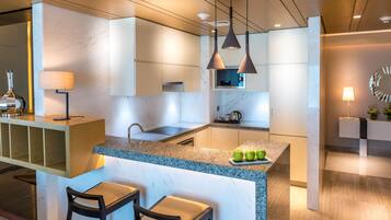 Une cuisine moderne dotée d’un îlot central, de tabourets de bar, de luminaires suspendus et d’un pare-feu en marbre.