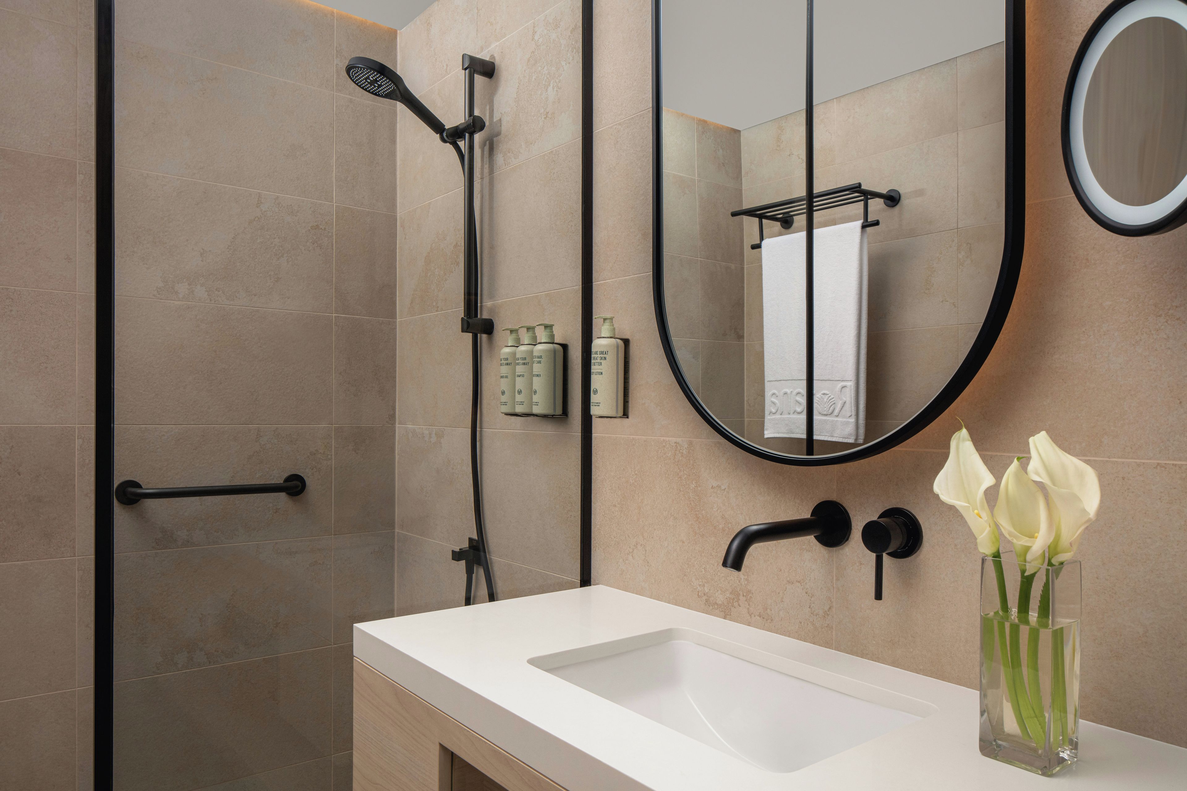 Un baño moderno con ducha, lavamanos y espejo.