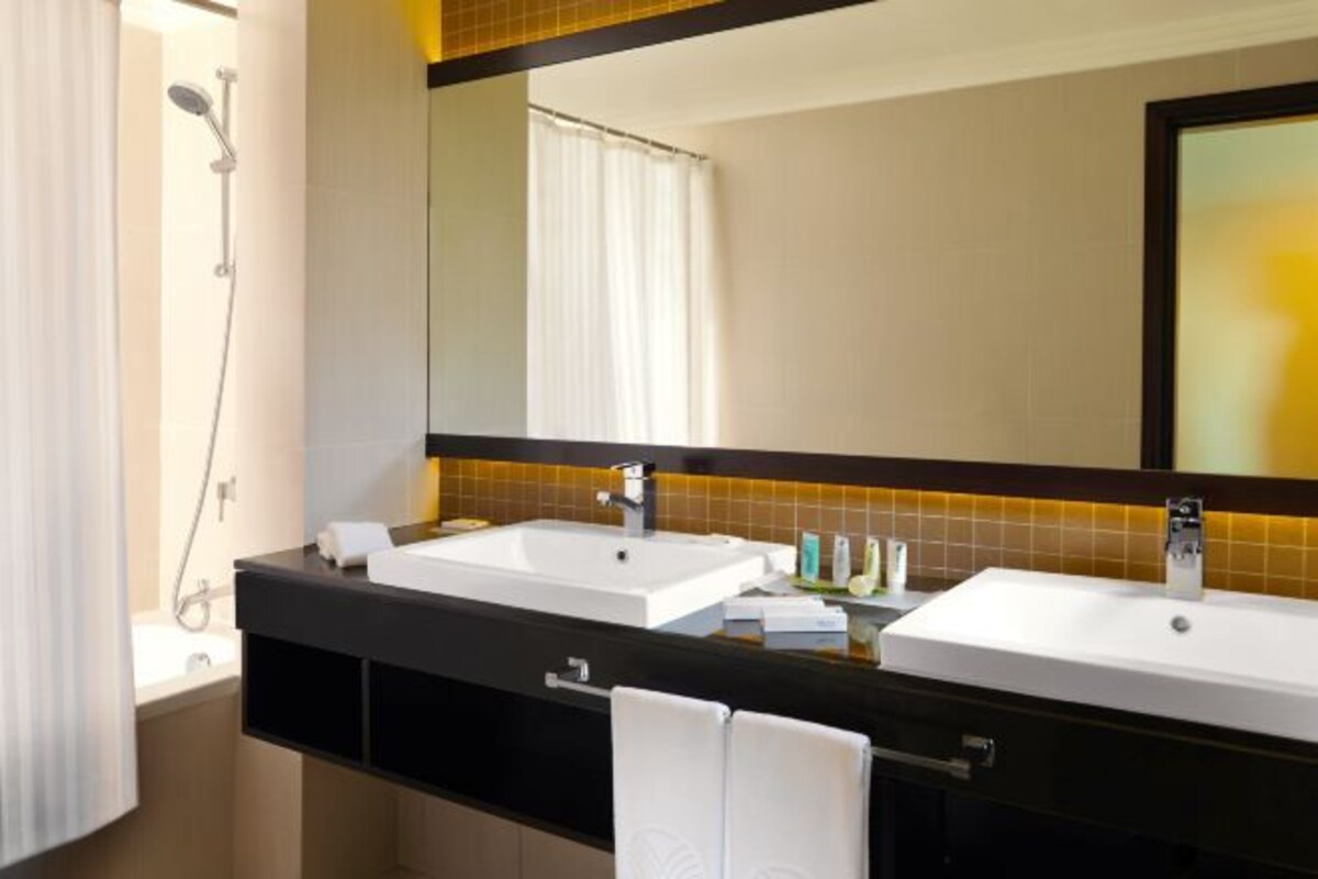 A bathroom with two sinks, a shower, and a large mirror.