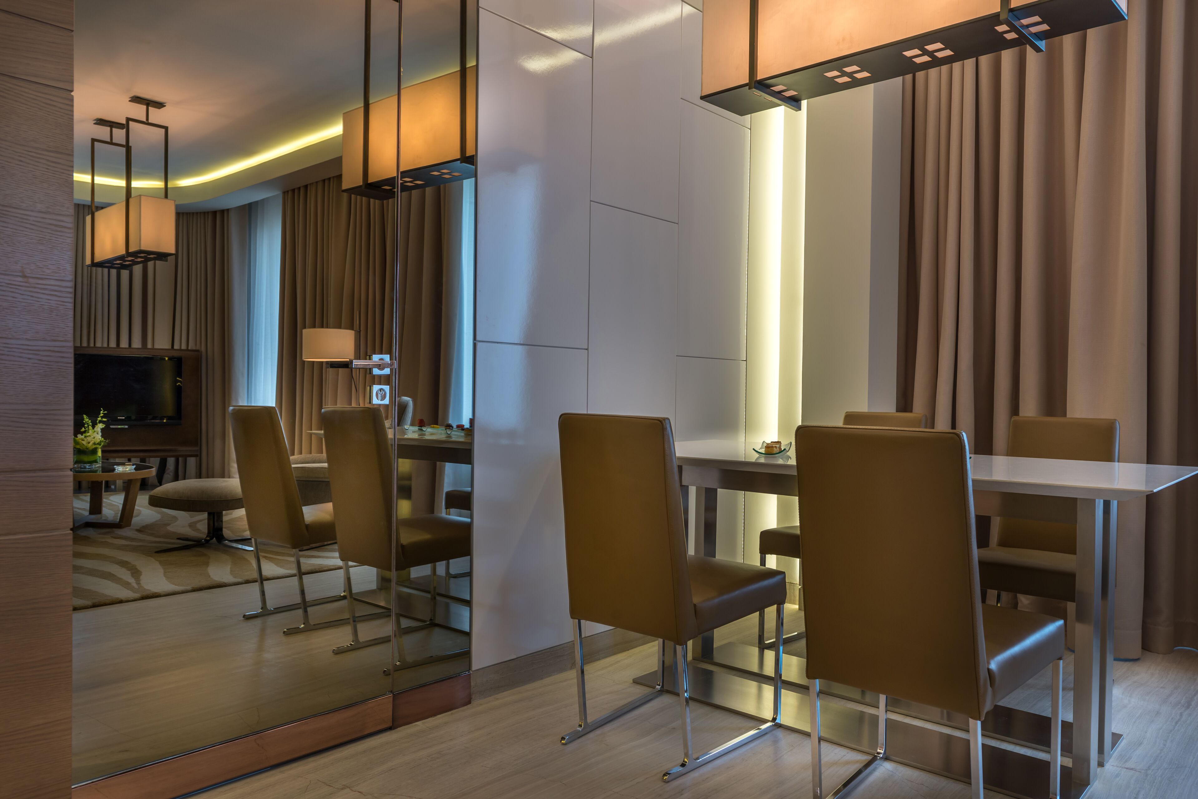 Une chambre d’hôtel moderne dotée d’un coin repas, d’un téléviseur à écran plat et d’un grand miroir.