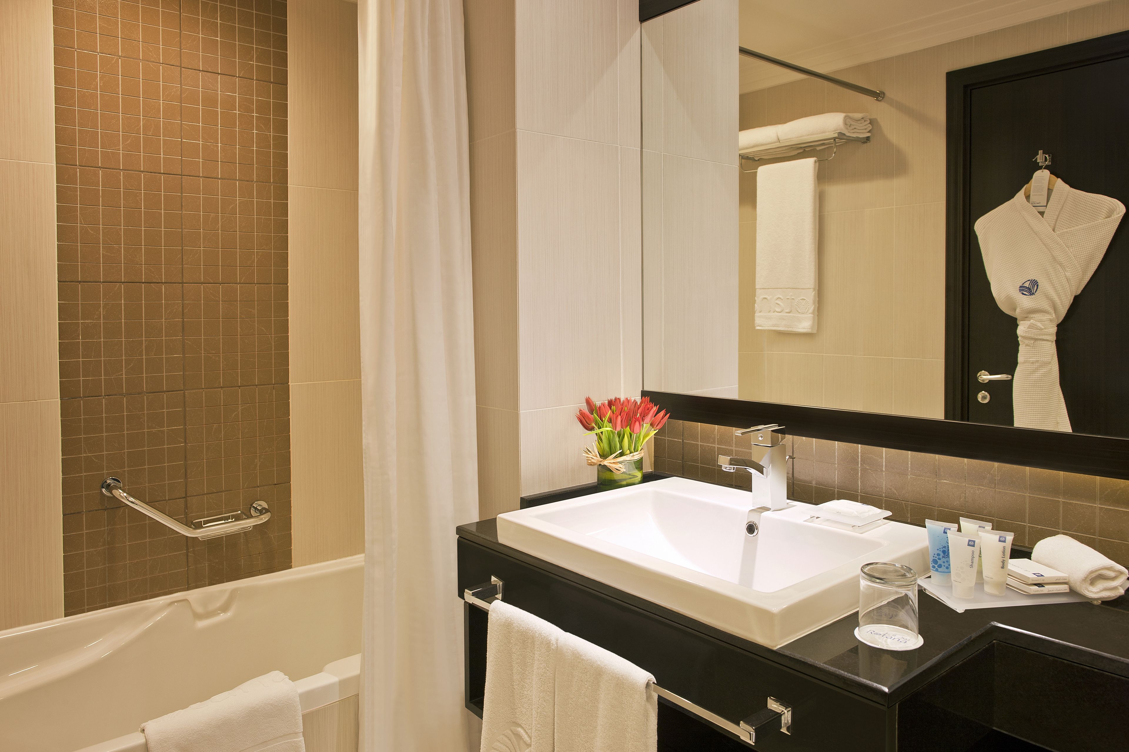 A modern bathroom with a bathtub, a sink, and a mirror.