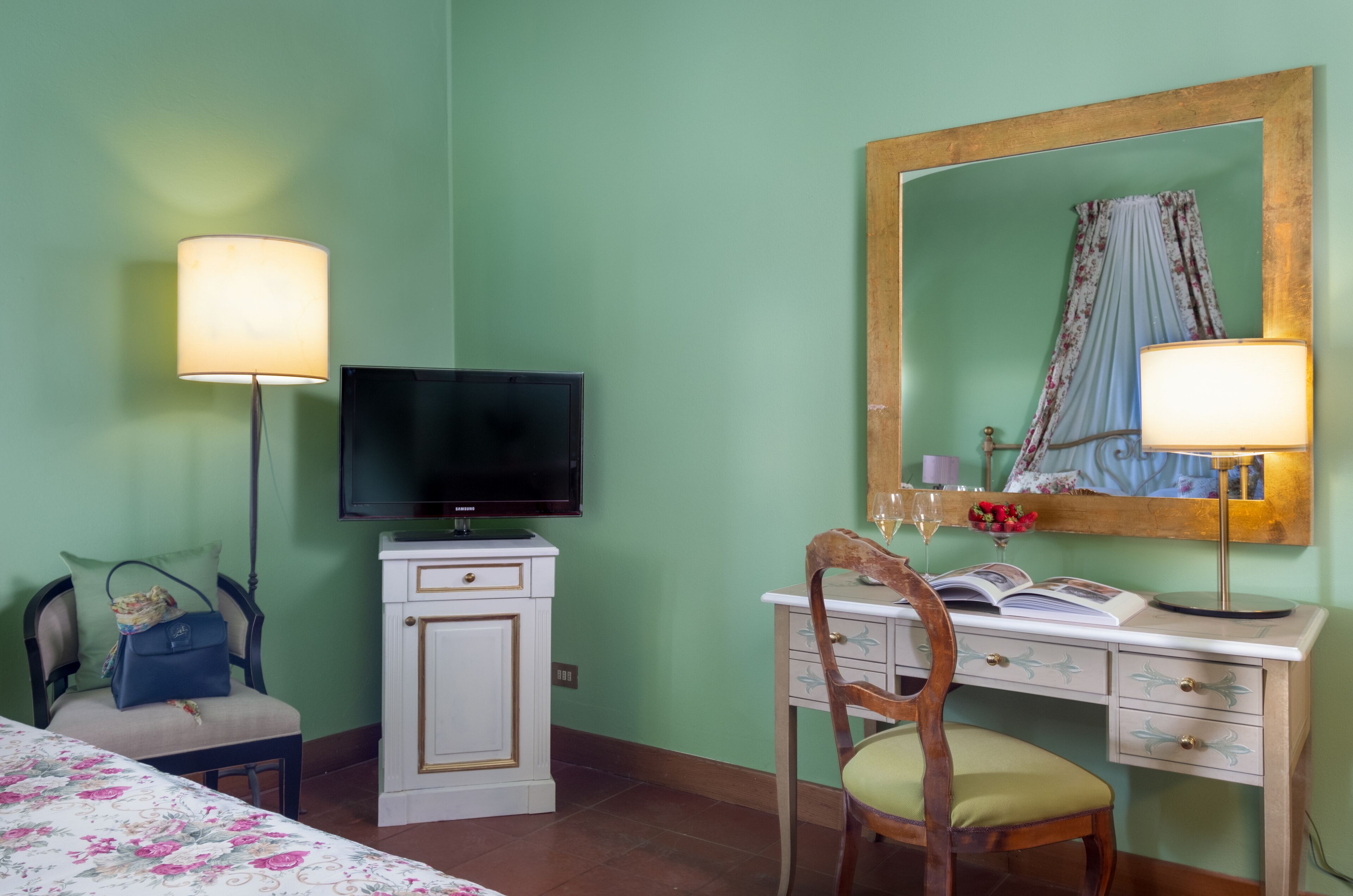 Une pièce comprenant un lit, un bureau avec une chaise, une télévision, un miroir et une lampe.