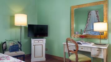 Une pièce comprenant un lit, un bureau avec une chaise, une télévision, un miroir et une lampe.