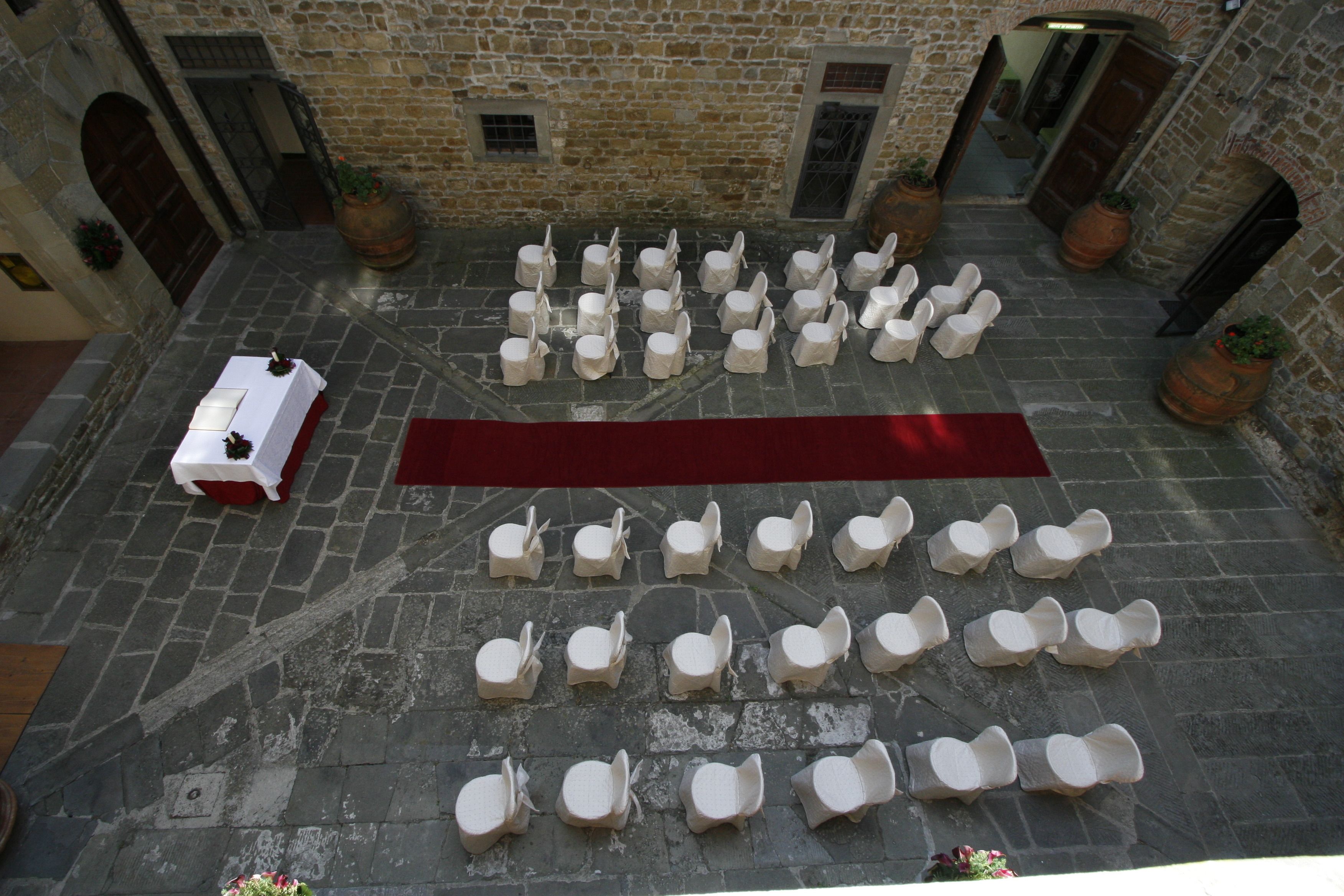 Un patio con suelo de piedra, mobiliario dispuesto y alfombra roja.