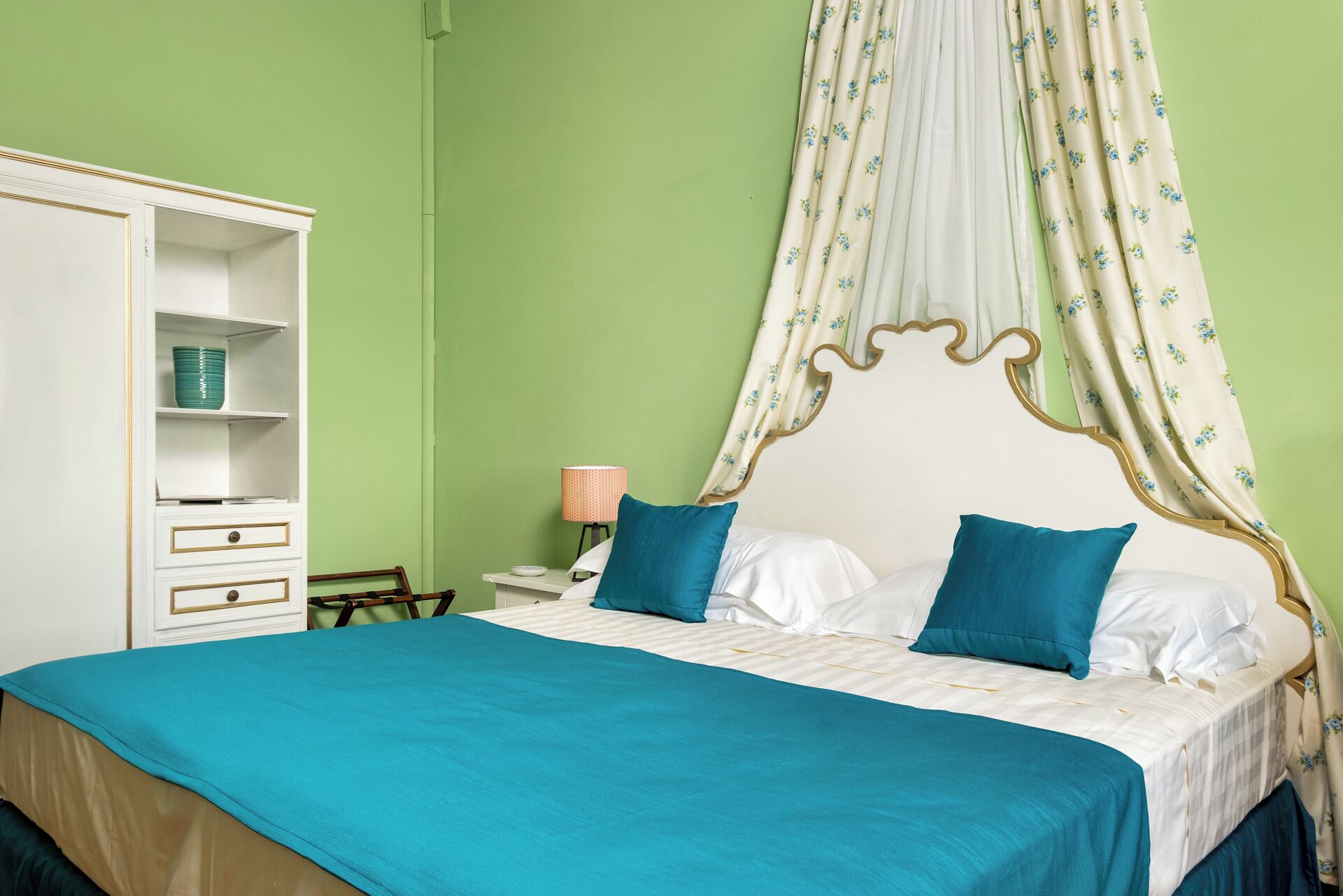 Une chambre à coucher avec un lit à baldaquin, une armoire et une table de chevet avec une lampe.