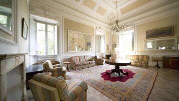 A spacious living room with a large rug, multiple seating options, and a fireplace.