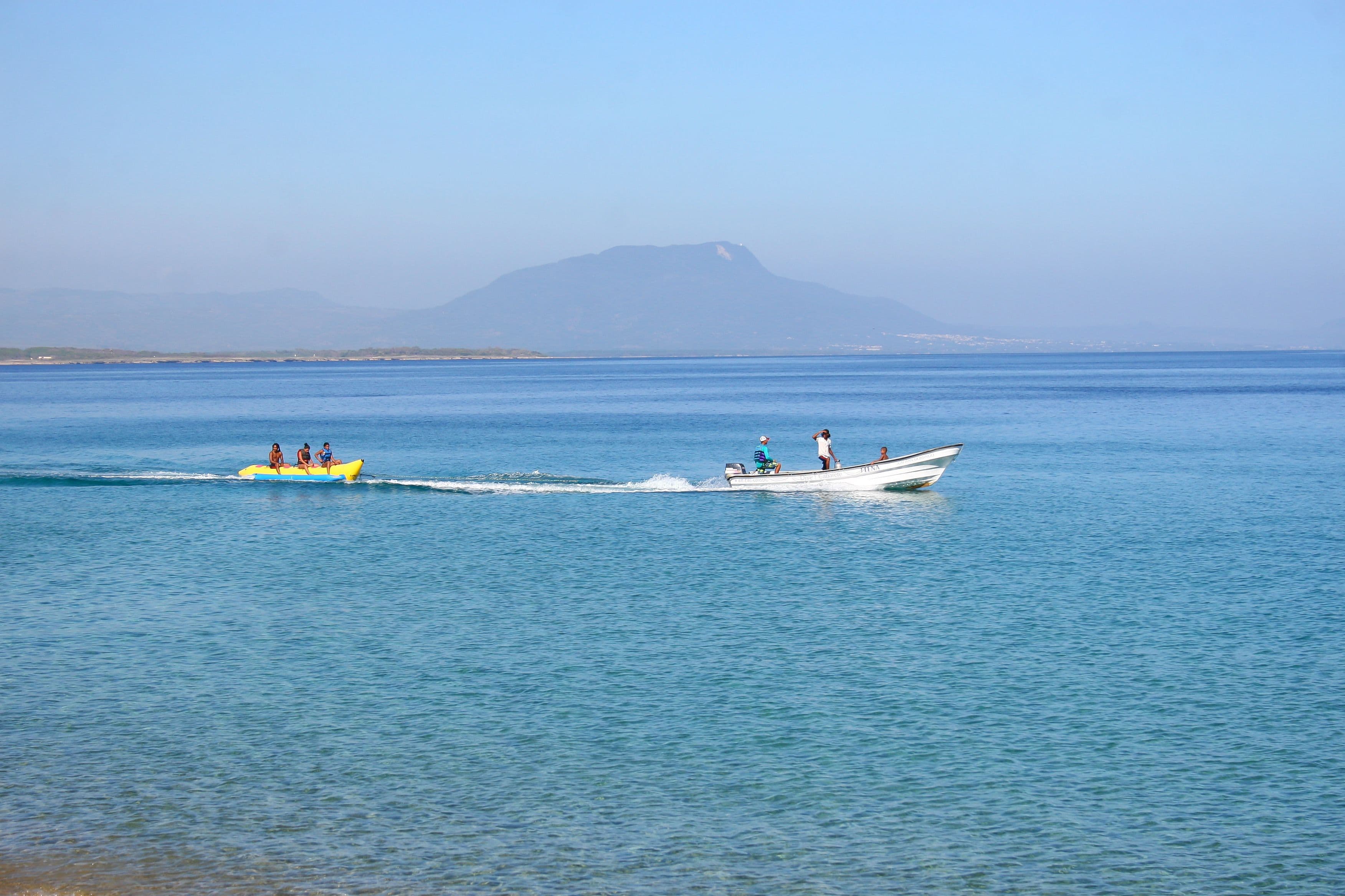 A calm body of water with a boat and a yellow inflatable raft.