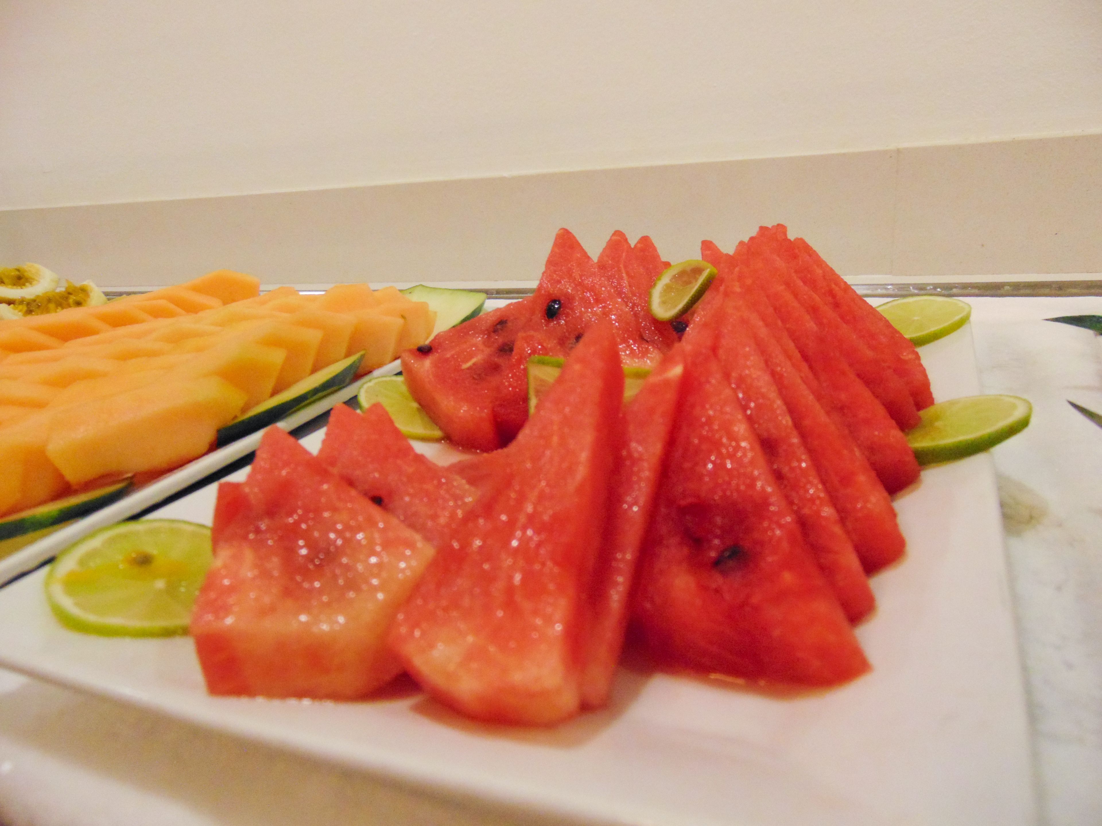 A plate of watermelon and cantaloupe slices with lime wedges.