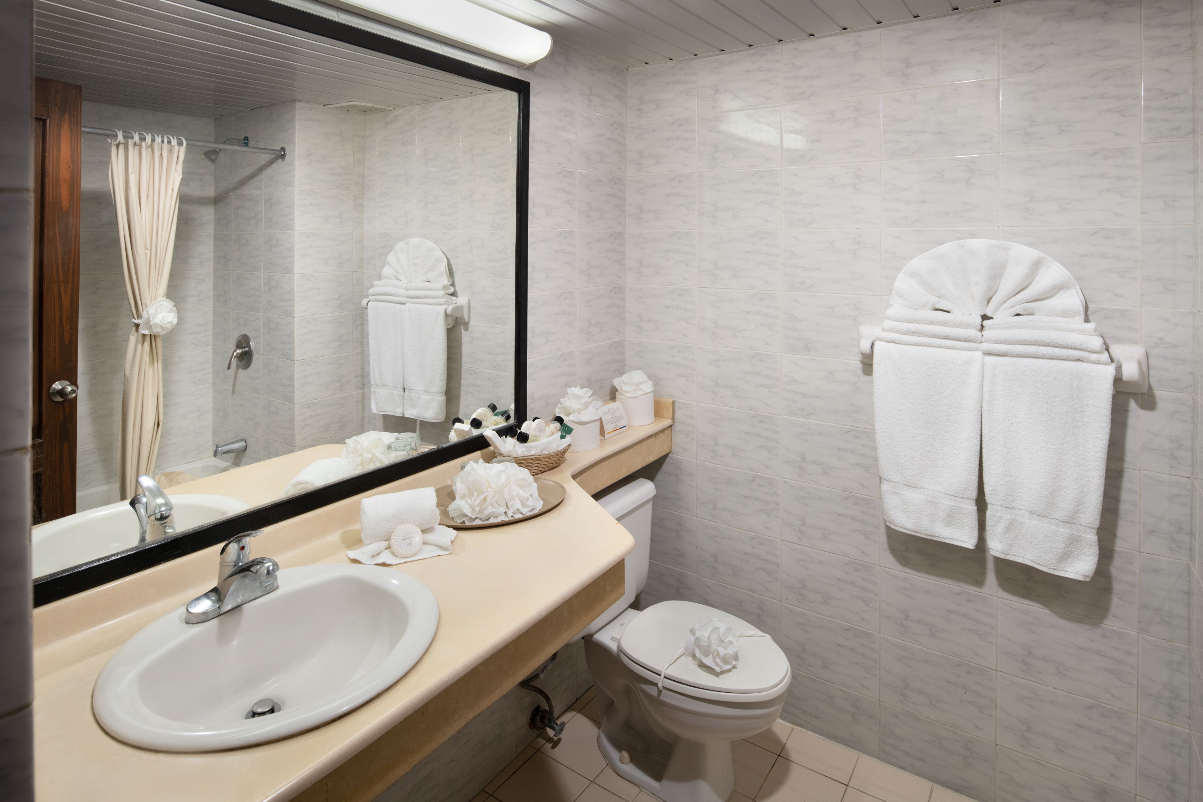 A modern bathroom with a sink, mirror, toilet, and towel rack.