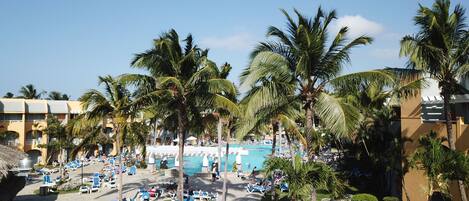 A resort with a central pool, palm trees, and lounge chairs.
