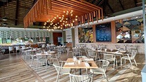 A spacious restaurant with wooden flooring, white chairs, and hanging pendant lights. - Casa Marina Sosua, Trademark by Wyndham Resort (Sosúa)