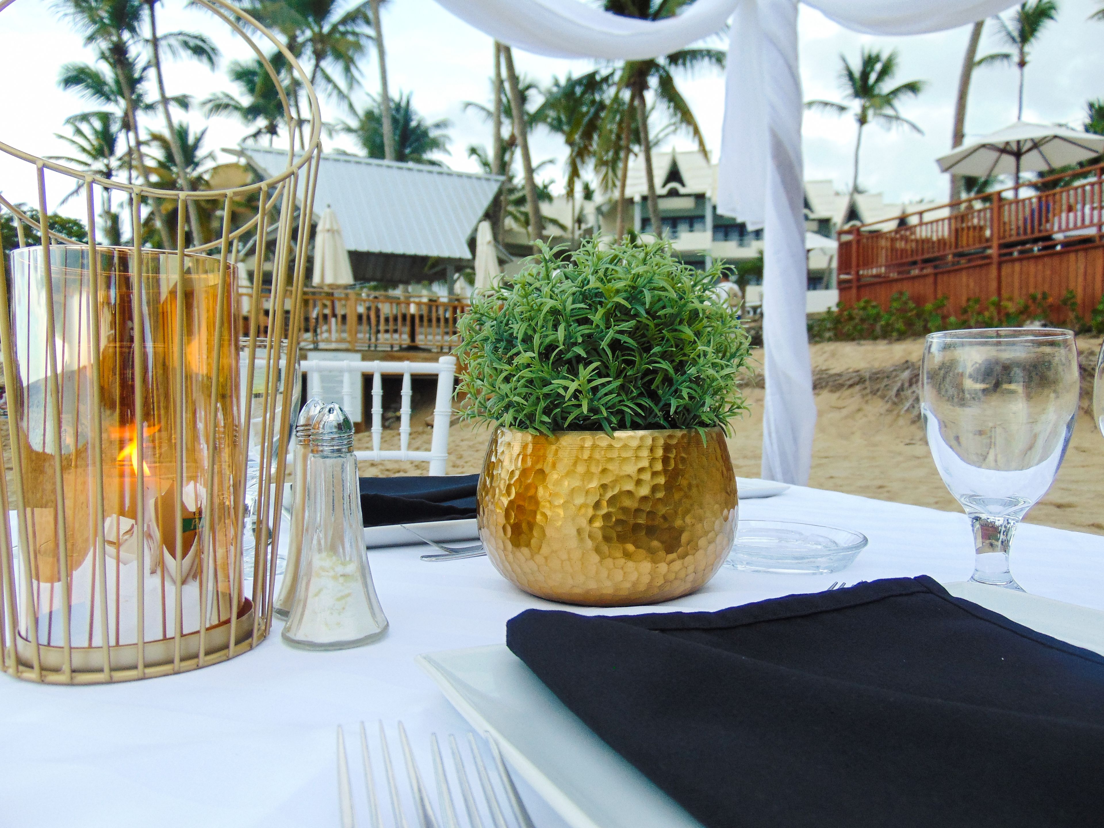 A table set for a meal with a gold textured centerpiece, salt and pepper shakers, and a glass of water.