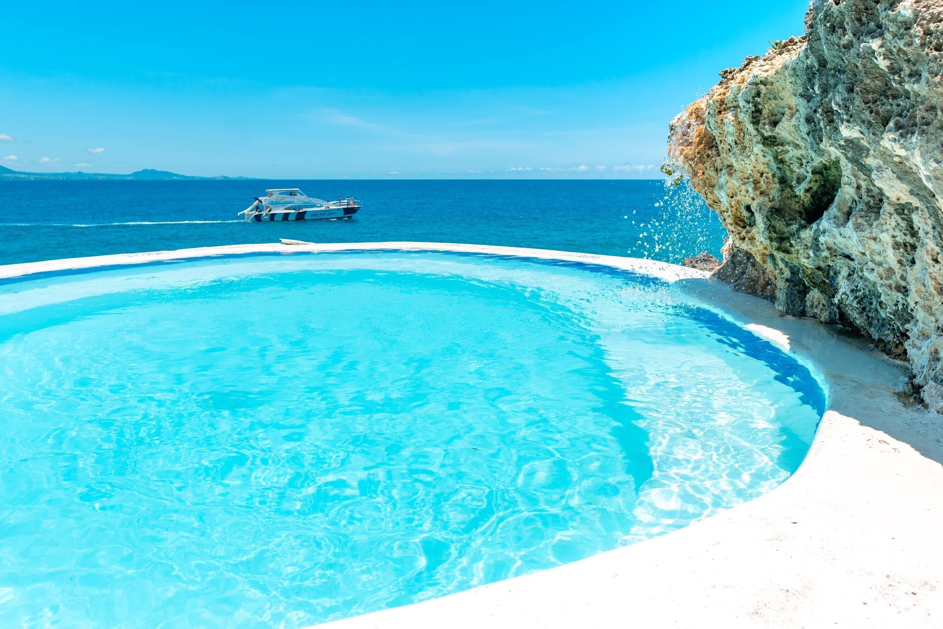 A clear blue pool with a boat in the background.