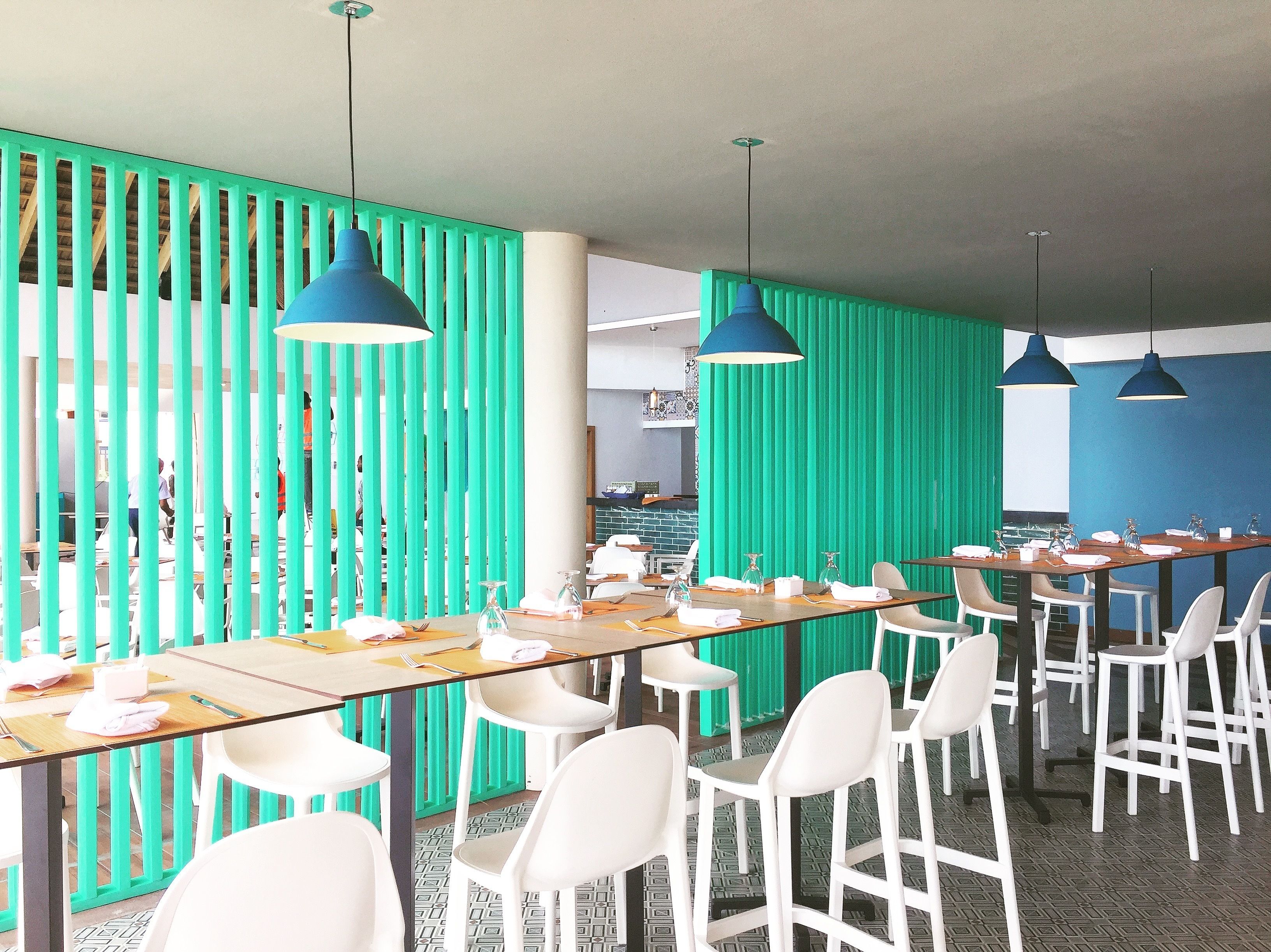 A modern meeting room with long tables, white chairs, and blue pendant lights.