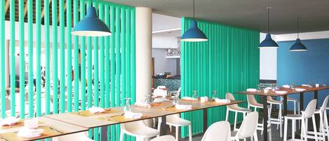 A modern meeting room with long tables, white chairs, and blue pendant lights.