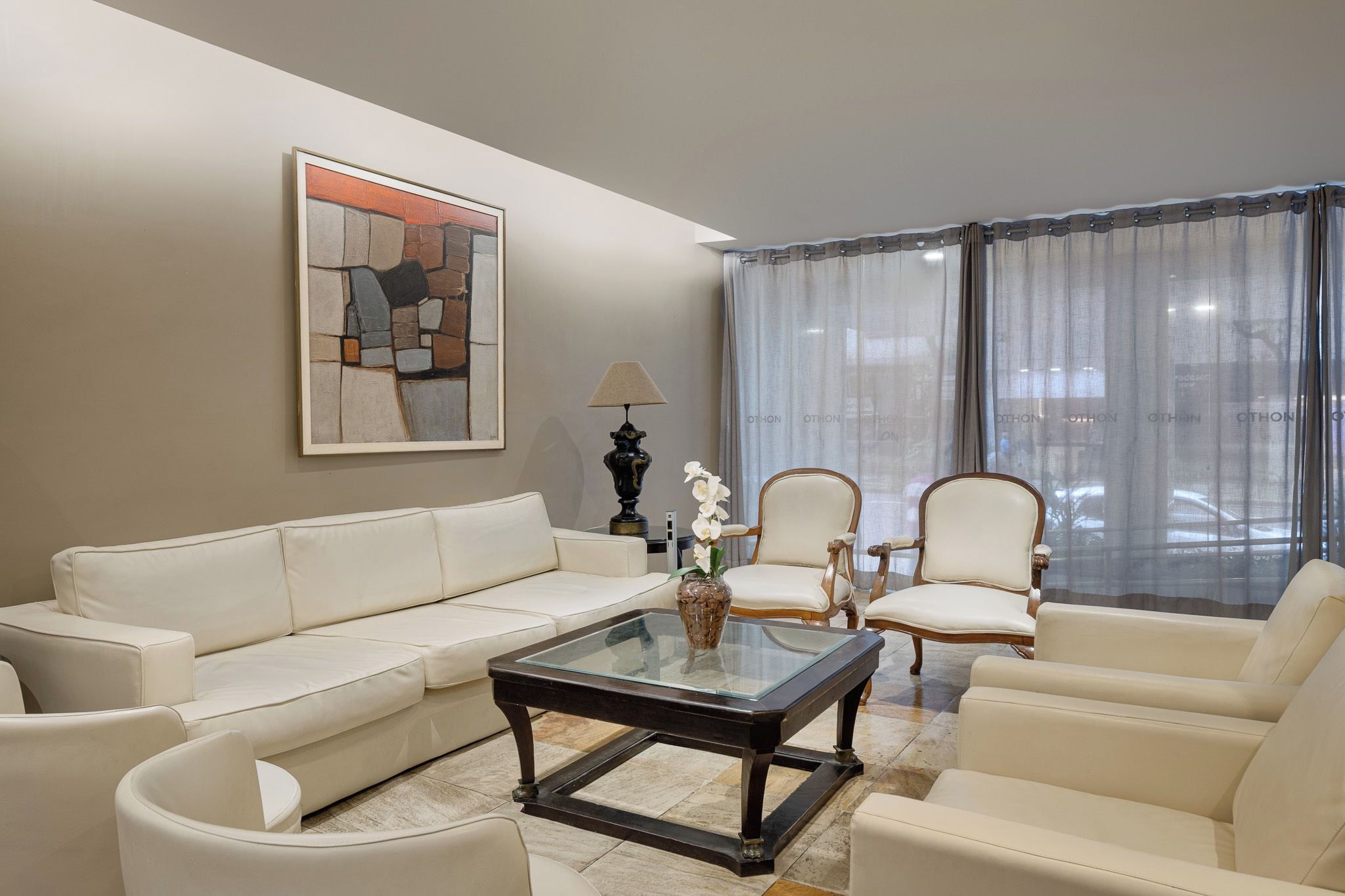 A living room with a sofa, two armchairs, a coffee table, and a painting on the wall.