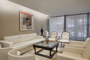 A living room with a sofa, two armchairs, a coffee table, and a painting on the wall. - Savoy Othon Lite (Rio de Janeiro)