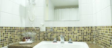 A bathroom with a white sink, two faucets, a hairdryer, and a mirror.