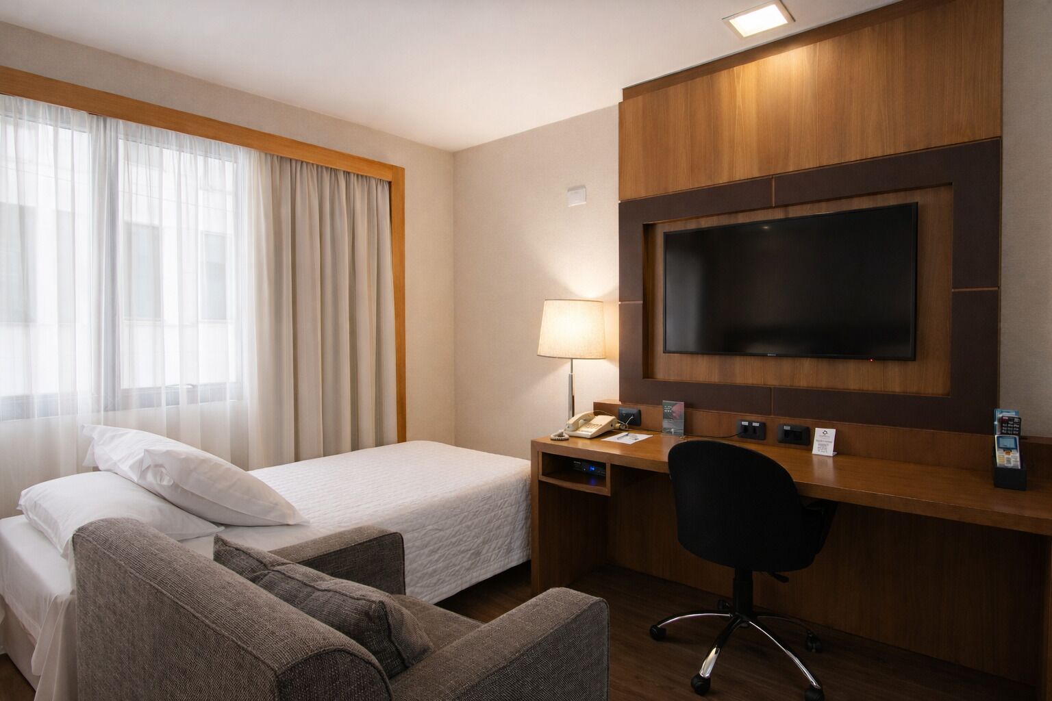 Ett hotellrum med två sängar, ett skrivbord med en TV, en lampa och en stol.