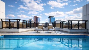 A rooftop pool with two lounge chairs and a city view. - Transamerica Executive Faria Lima (São Paulo)