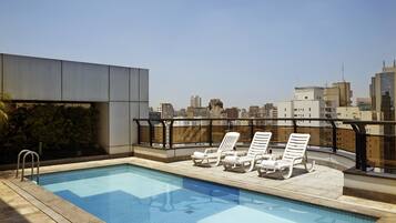 Alberca al aire libre, sombrillas en la alberca y camastros