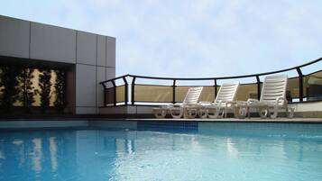 Una piscina al aire libre, sombrillas, sillones reclinables de piscina