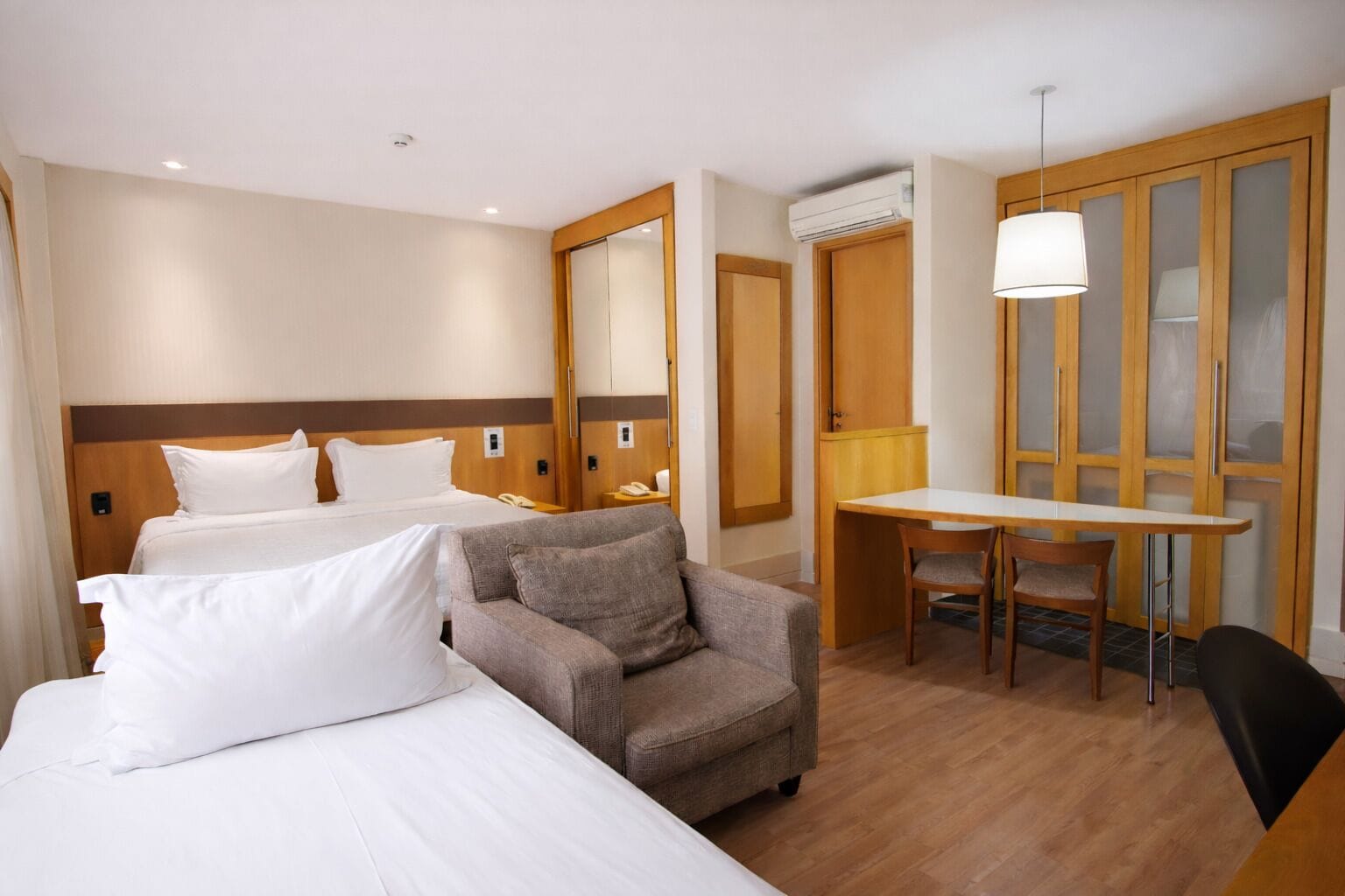 A hotel room with two beds, a sofa, a desk, and a chair.