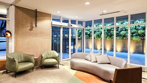 Un hall d’entrée moderne avec un canapé, des fauteuils et une table basse.