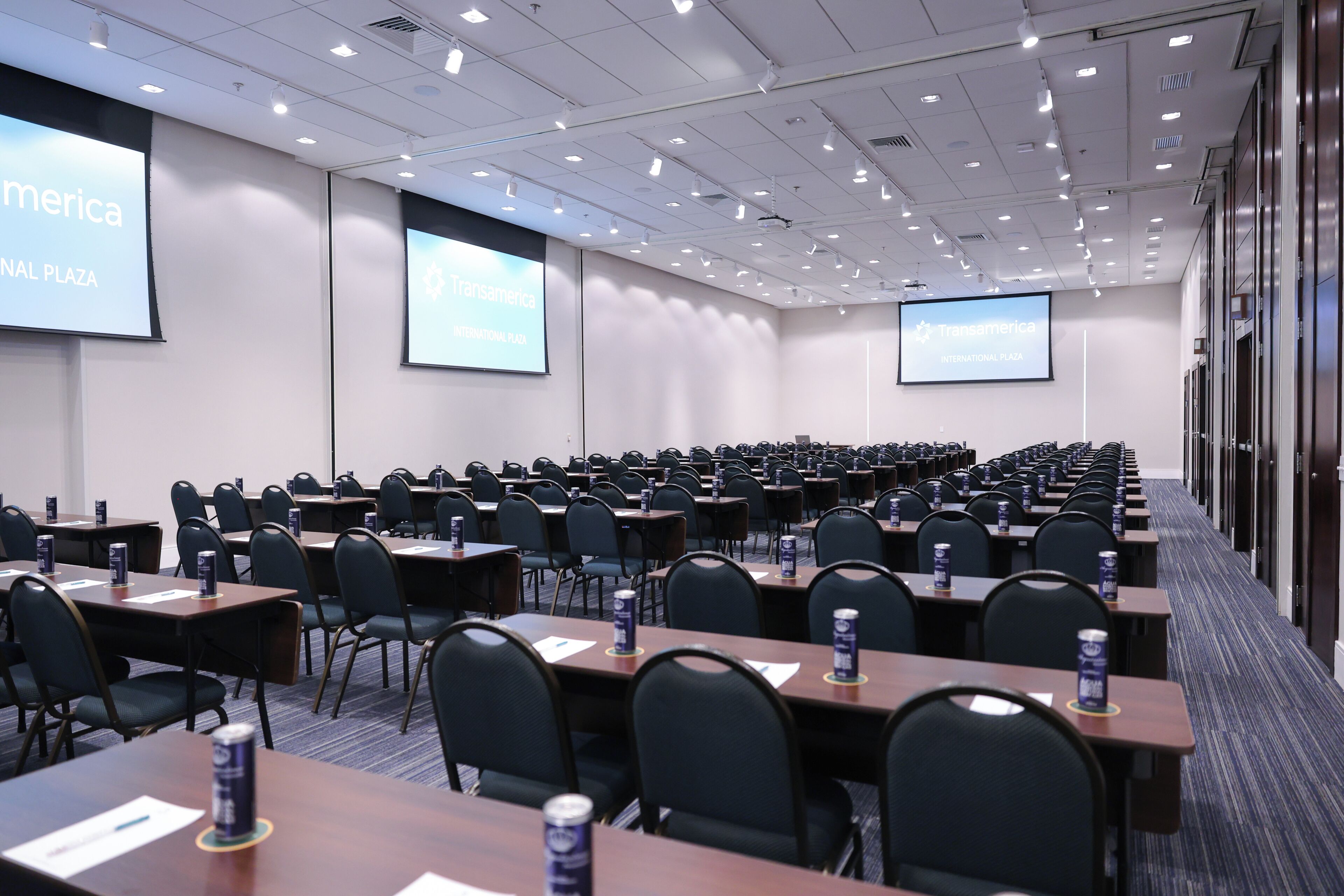 A conference room with rows of tables, chairs, and presentation screens.