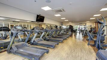 A gym with multiple treadmills, exercise equipment, and a large mirror on the wall.