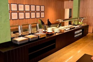 Een buffetopstelling met diverse voedselcontainers en een wand vol ingelijste certificaten.