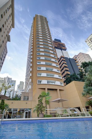 Hotel alto com piscina e área de estar ao ar livre.