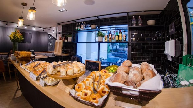 A breakfast buffet with various pastries and bread, a coffee station, and a view of the outdoors. - Transamerica Executive Bela Cintra (São Paulo)