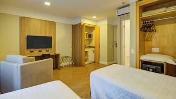 Ett hotellrum med två sängar, ett skrivbord, en tv och en garderob.