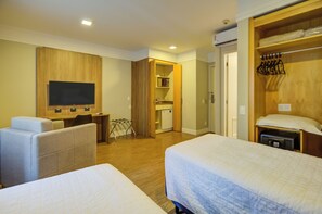 A hotel room with two beds, a desk, a television, and a wardrobe.