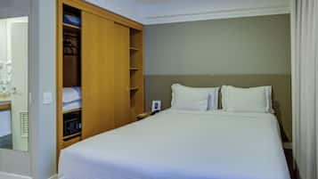 A hotel room with a large bed, a wooden wardrobe, and a bedside table.