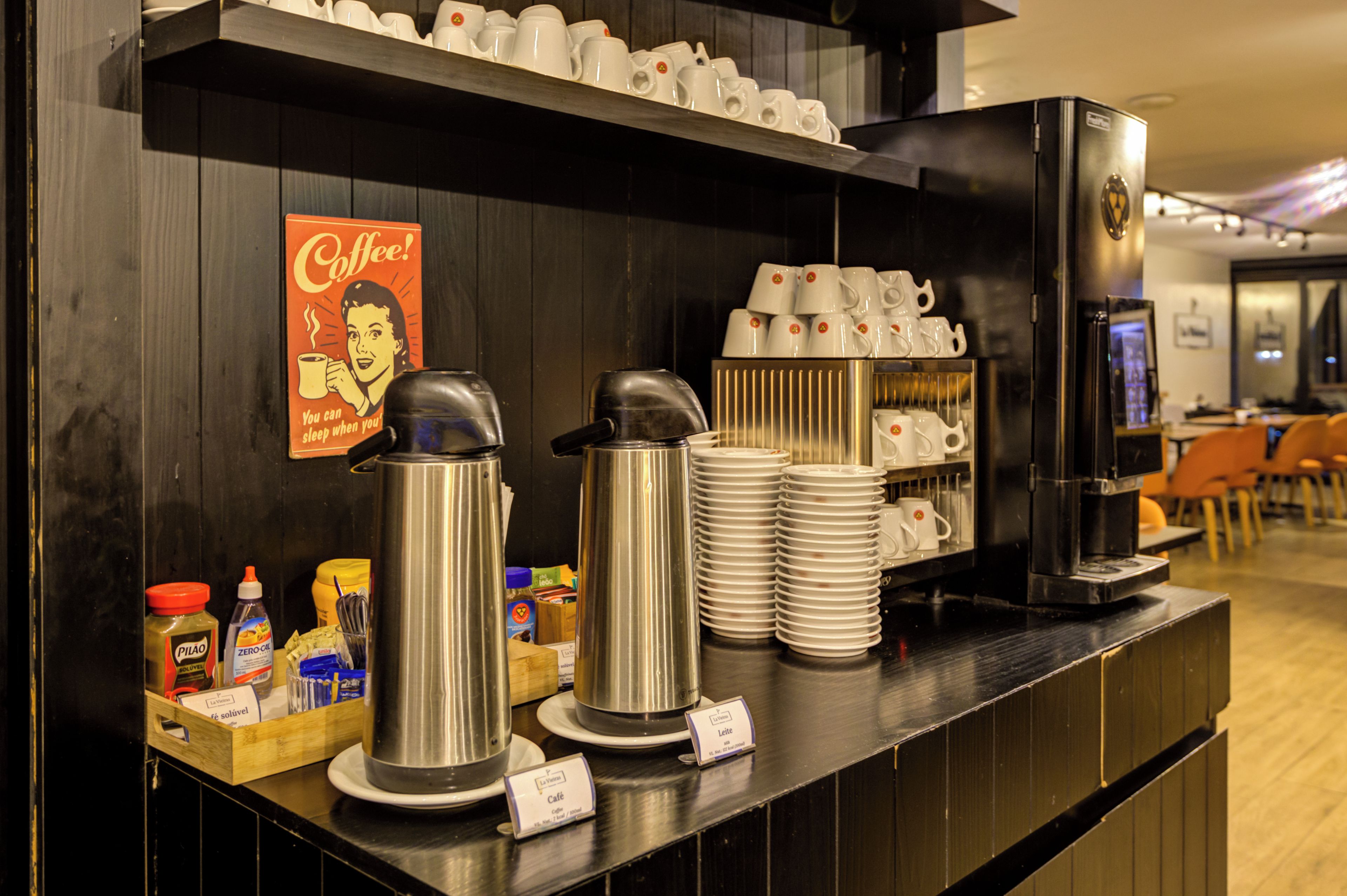 Una estación de café con una cafetera, tazas y un letrero.