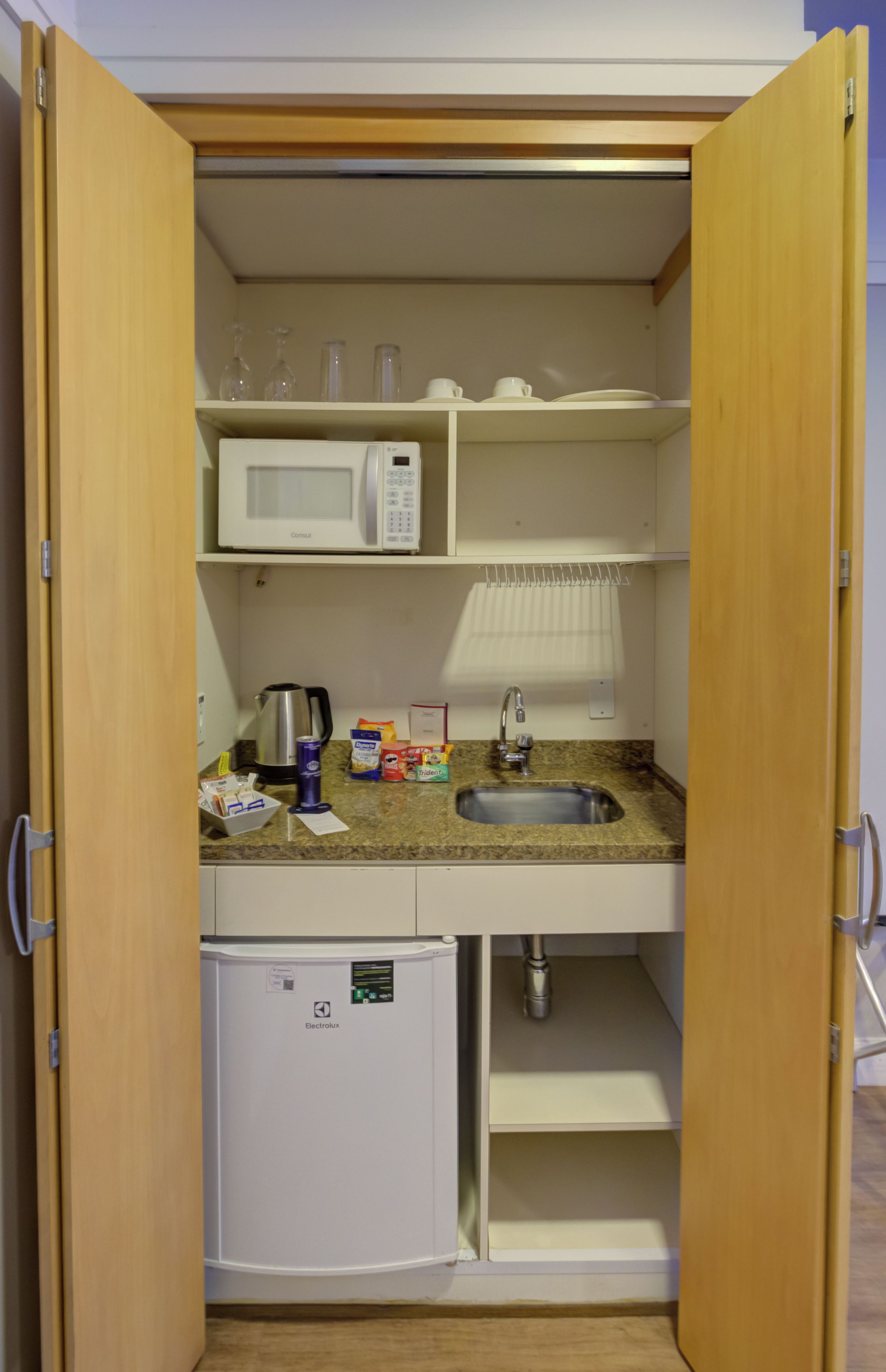 A compact kitchenette with a microwave, sink, and small refrigerator.
