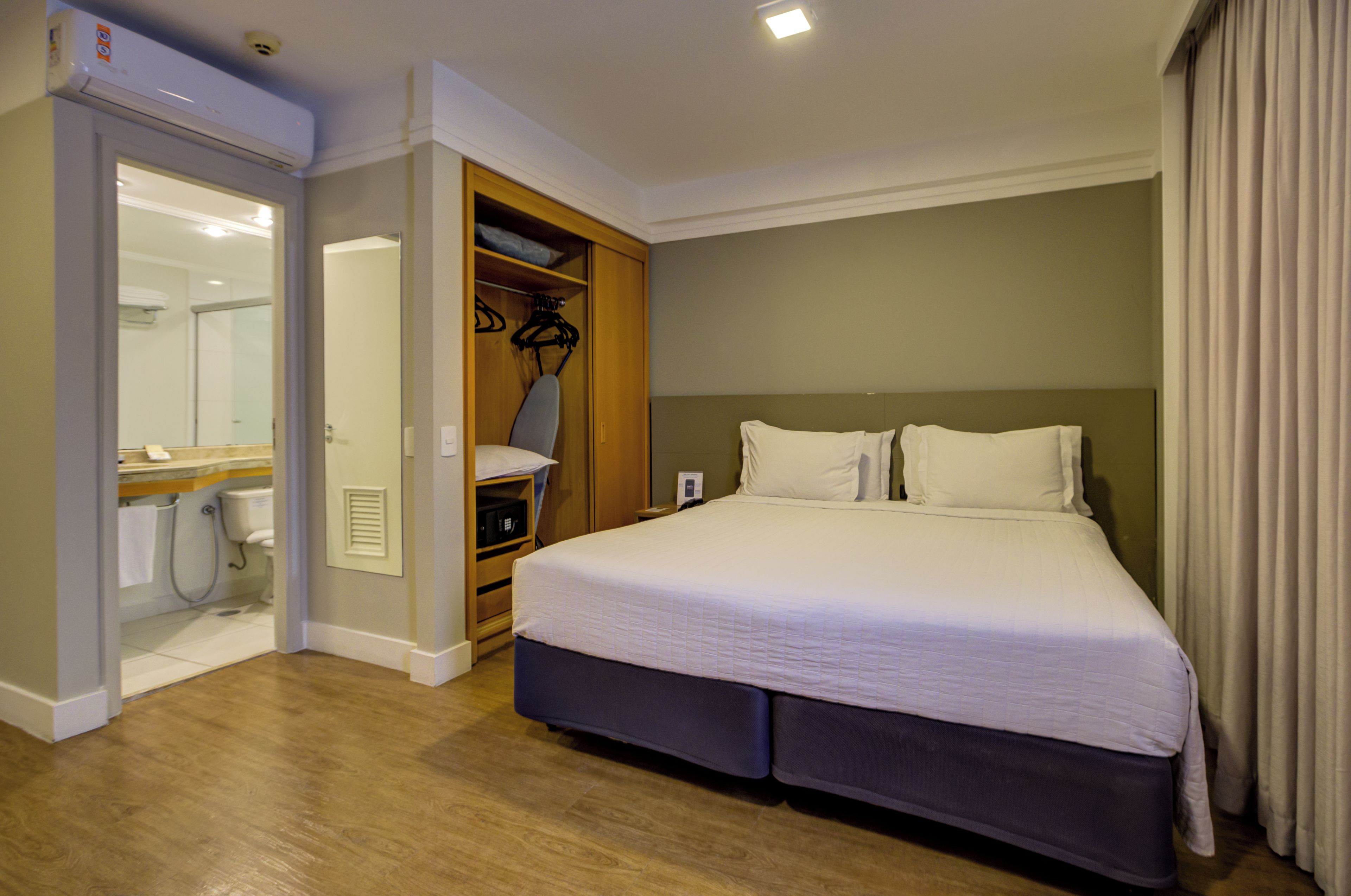 Quarto de hotel com cama, closet espaçoso e banheiro.