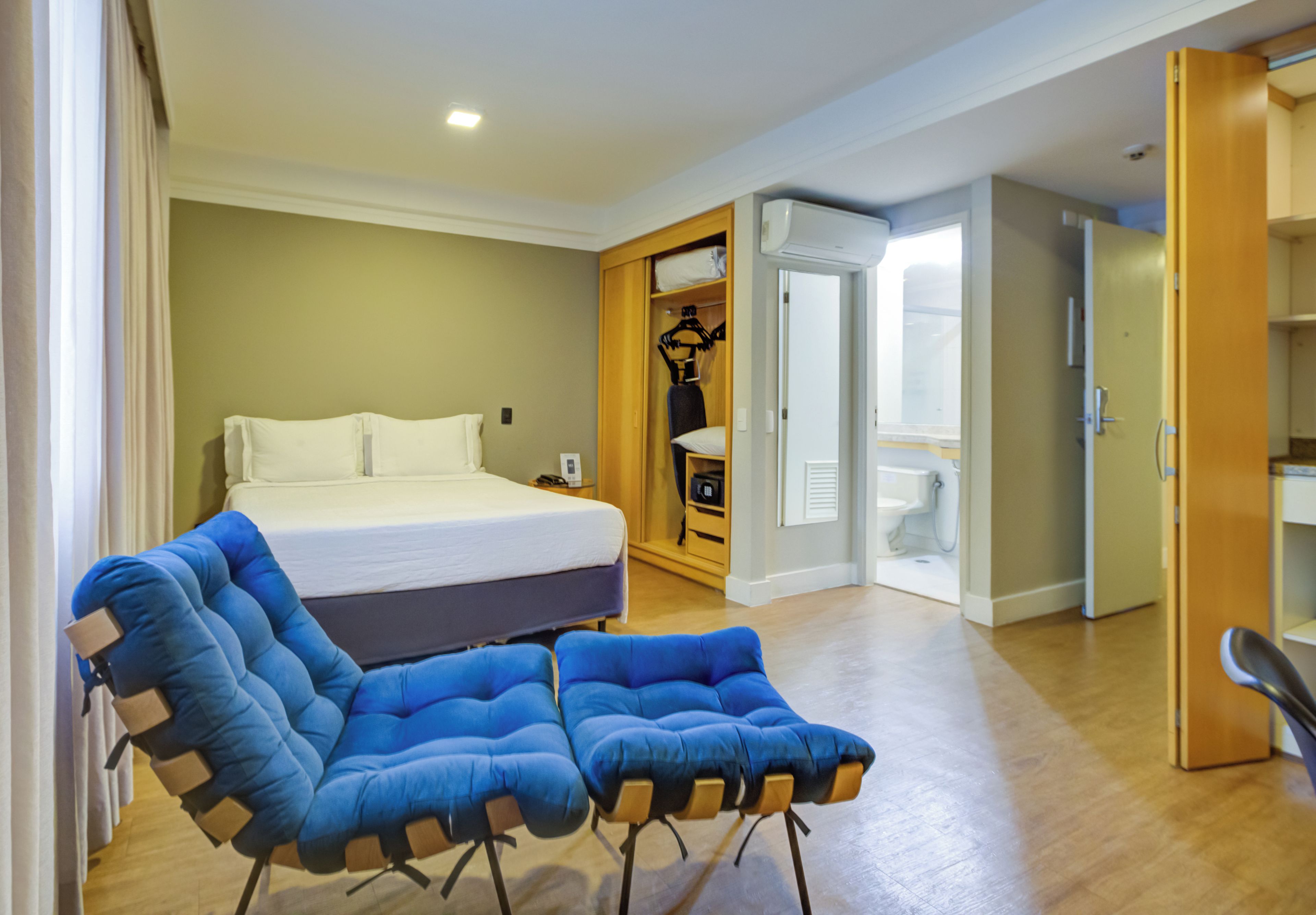 A bedroom with a bed, a wardrobe, and a seating area.